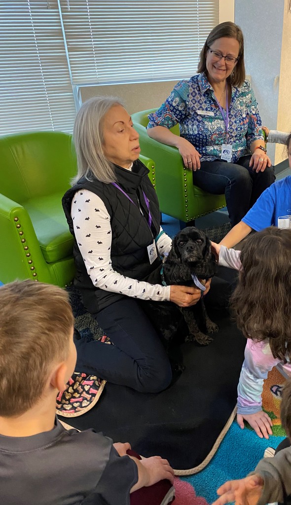 A reading therapy dog visits an elementary library and students